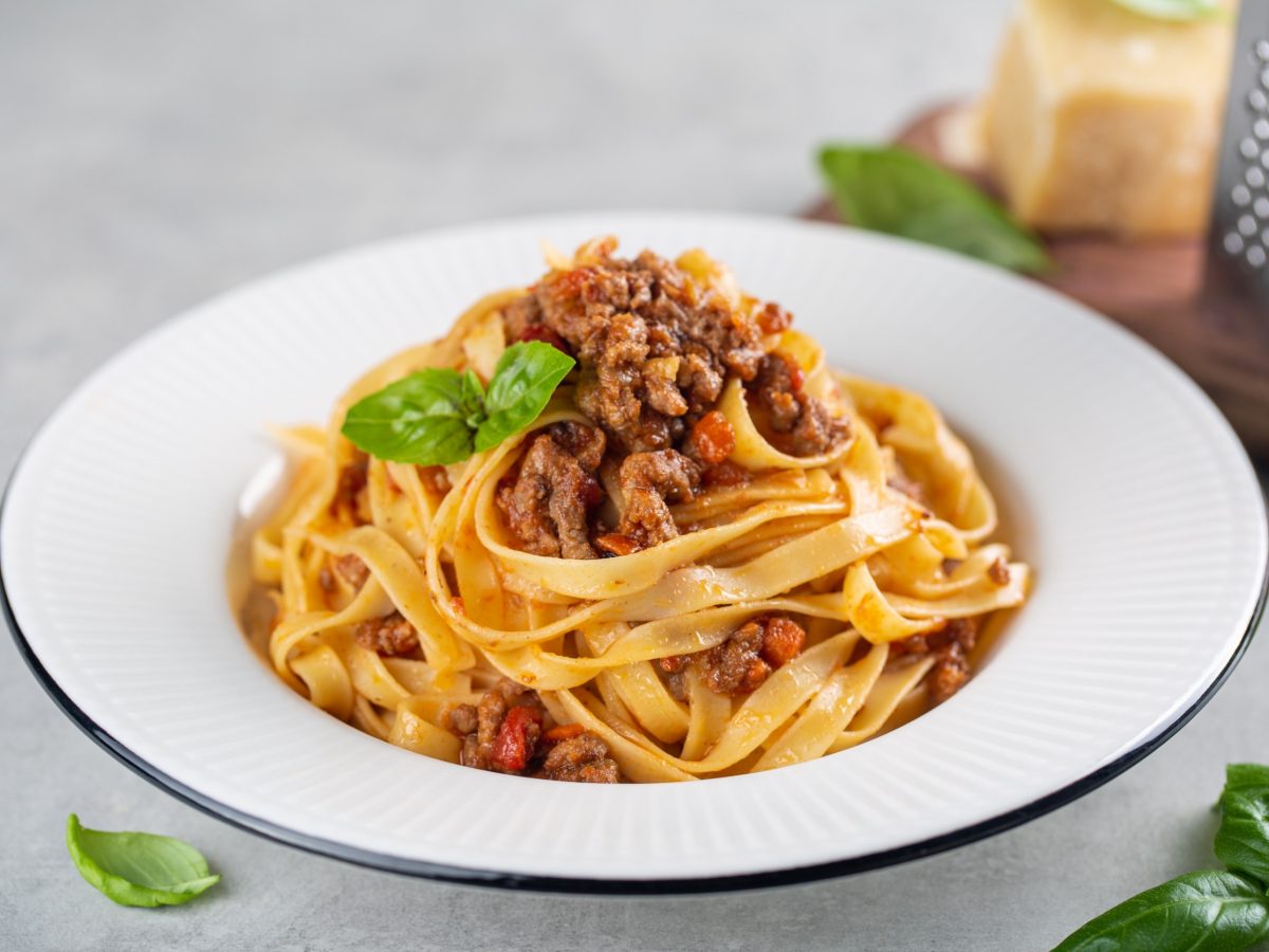 Tagliatelle al ragu - italian pasta with meat bolognese sauce. High angel. Extra hard cheese on background.